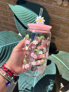 a person holding up a glass with flowers on it and a straw in the cup