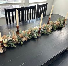 the table is set with candles and greenery for an elegant touch to the dining room