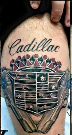 the back of a man's leg with tattoos on it and an image of cadillac