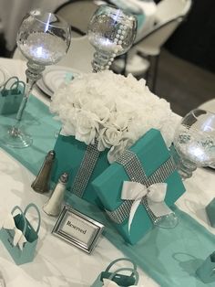 the table is set with blue and white flowers, silverware, and gift boxes