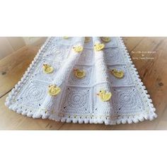 a white crocheted blanket with ducks on it and a wooden floor in the background