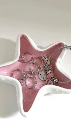 a pink and white star shaped tray with lots of jewelry on it's side