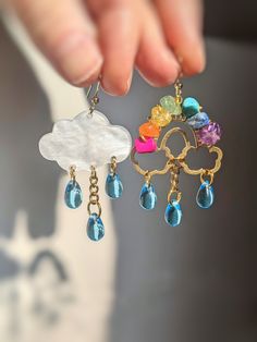 Adorable handcrafted Rain Cloud & Rainbow earrings.🌧️🌈✨ The perfect accessory for lightweight comfortable every day wear. This is a purposely mismatched pair, one cloud pendant and one crystal wire wrapped rainbow pendant with crystal glass teardrop beads. The rainbow is wrapped with Pink Howlite, Red Aventurine, Citrine, Green Aventurine, Lapis Lazuli, Turquoise Howlite and Amethyst. The pendants are dangling on 18k gold plated hypoallergenic fish hook earring wire. Handmade with love! 💗🌸 * Teacher Earrings, Cloud Earrings, Rainbow Rain, Rain Cloud, Jewelry Summer, Summer Earrings, Boho Accessories, Crystal Suncatchers, Rainbow Crystal