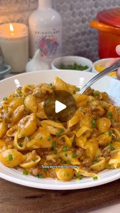 a person is holding a fork over pasta with meat and sauce on a white plate