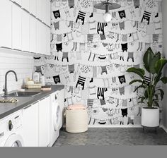 a white kitchen with black and white wallpaper on the walls next to a washer and dryer