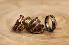 three different types of wedding rings sitting on top of a wooden table