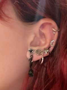 a close up of a person with red hair and piercings on their ears wearing ear rings