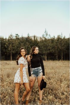 two young women are standing in a field