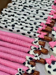 pink and black decorated doughnuts lined up in rows on white trays with polka dots