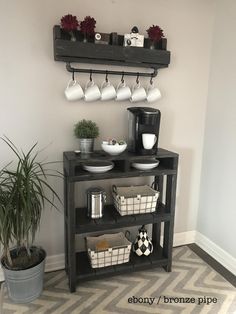 a coffee bar with cups and mugs on the top shelf next to potted plants