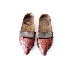 This is a pair of antique wooden clogs. The hand-carved wood sabot feature a red lacquer paint with leather straps across the arch. Vintage Closed Toe Mules With Leather Sole, Traditional Closed Toe Clogs With Leather Sole, Vintage Clogs With Leather Sole And Closed Toe, Vintage Leather Sole Closed Toe Clogs, Vintage Closed Toe Clogs With Leather Sole, Traditional Leather Clogs With Rubber Sole, Traditional Leather Clogs With Closed Toe, Traditional Leather Closed-toe Clogs, Traditional Leather Closed Toe Clogs