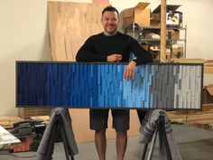 a man standing in front of a blue and gray box with wood panels on it