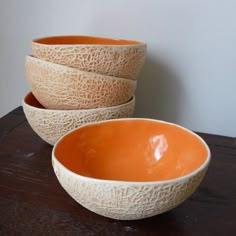 three orange bowls sitting on top of a wooden table