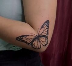 a woman's arm with a butterfly tattoo on the left side of her arm