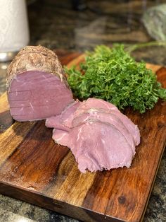 a wooden cutting board topped with meat and veggies on top of a counter