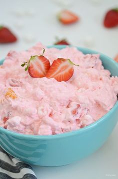 a blue bowl filled with strawberry fluff and topped with two strawberries