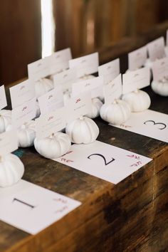 small white pumpkins are placed on top of each other with place cards in front of them