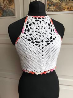 a white crocheted top on a mannequin with an orange and pink trim