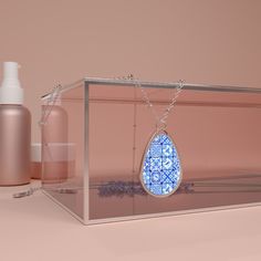 a clear box with a blue and white tear shaped pendant hanging from it's side