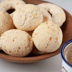 a bowl filled with doughnuts next to a cup of coffee