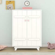 a white cabinet sitting in the corner of a room next to a teddy bear and clock