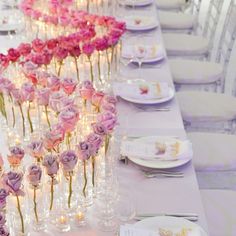 a long table is set with pink roses and candles for an elegant wedding reception or special event