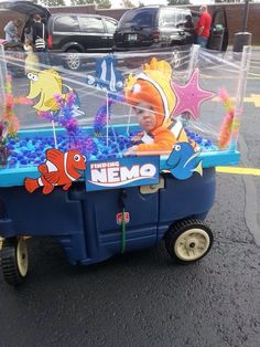 a child in an aquarium cart with fish and bubbles on the top, sitting outside