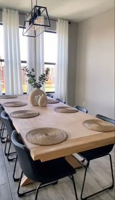 a dining room table with place settings on it and windows in the backround