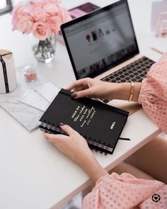 a woman sitting at a desk with a laptop and notebook