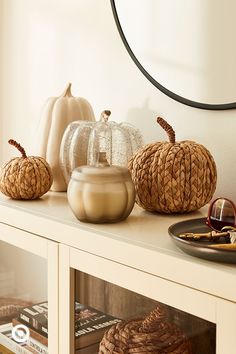 some pumpkins are sitting on top of a white shelf in front of a mirror