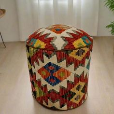 a colorful ottoman sitting on top of a wooden floor next to a potted plant