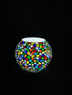 a colorful glass bowl sitting on top of a black surface with lots of small squares in it