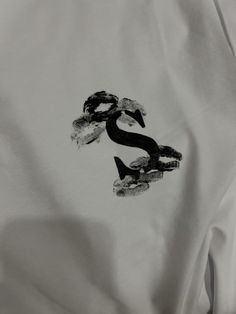 a white shirt with an image of a snake on the chest and black letters that read s