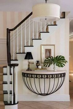 an entryway with a table and lamp next to the stairs