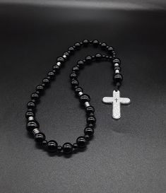 A very unique black Anglican Rosary that brings with it the power of the night prayer. The rosary is made of high quality Black Onyx gemstones, Miyuki Seed beads (which have been cleansed and purified) and a 304 Stainless Silver Cross with the Lord's Prayer engraved on it. Finally, the rosary has been blessed by the church. A rosary made to accompany you during your night prayers. Rosary: Anglican configuration Blessed: Yes About the Rosary: The Rosary has a Cross, an Invitatory bead, 4 sets of Black Hematite Jewelry With 8mm Beads, Spiritual Black Onyx Necklaces, Spiritual Black Onyx Necklace, Black 8mm Beads For Gifts, Black Hematite Spiritual Jewelry, Black Spiritual Beaded Jewelry, Black Hematite Jewelry For Meditation, Black Obsidian Necklace With 8mm Beads, Black Polished Beads Necklace For Meditation