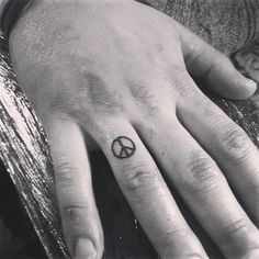 a person's hand with a peace sign tattoo on it