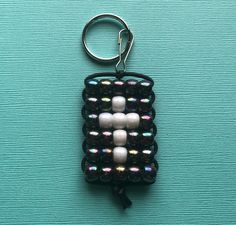 a keychain made out of beads on top of a blue surface with a black cord