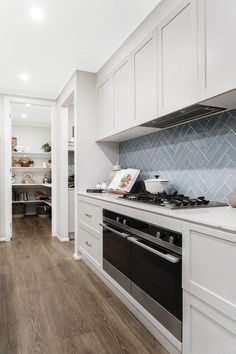 a kitchen with white cabinets and wood floors