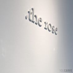 the word'the rose'is cut out of white paper and placed on a wall