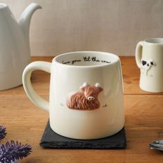 there is a coffee cup with a cow on it and two mugs next to it