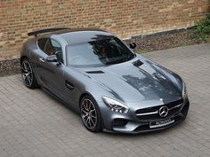 a grey mercedes sports car parked in front of a brick building