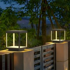 two lights that are sitting on top of some concrete blocks in front of trees and bushes