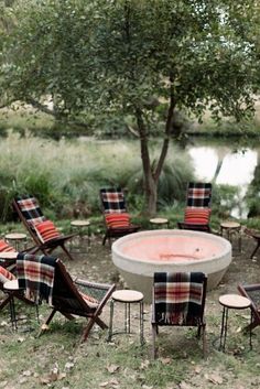 a fire pit surrounded by lawn chairs and tables in the middle of a grassy area