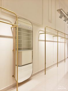 an empty room with white walls and gold metal racks on either side of the wall