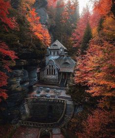 an old stone house surrounded by trees with fall foliage on the ground and in the foreground