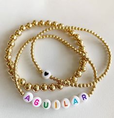 bracelet 1: plain 6mm bracelet 2: heart on 3mm beads bracelet 3: name on 3mm beads Choose ball finish & letter beads! will not tarnish! Cheap Birthday Name Bracelet With Heart Beads, Personalized Gold Jewelry With Colorful Beads, Everyday Gold Name Bracelet With Colorful Beads, Gold Heart-shaped Name Bracelet With Letter Beads, Everyday Yellow Gold Name Bracelet With Letter Beads, Collares Aesthetic, Silver Water, Gift Love, Letter Beads