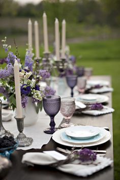 the table is set with purple and white plates, silverware, and lavender centerpieces