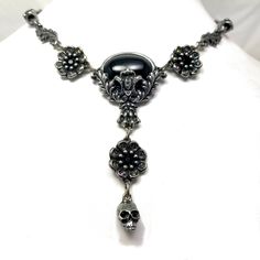 "Black cabochon stone with leaves and skulls with Black crystal eyes Flowers with Black crystal centers & Vitrail crystal details around Adjustable length 14-18\" Lead free pewter Always ethically sourced bones. Nothing has ever been harmed for the purpose of our jewelry. All pieces are made-to-order despite the \"in stock\" number in the listing. Time frame varies from piece to piece so please message us if you need something by a certain date and we will do our best. A portion of our profi Nickel-free Gunmetal Gothic Jewelry, Vintage Black Skull Jewelry, Black Skull Necklace With Oxidized Finish, Black Oxidized Skull Necklace, Gothic Oval Metal Jewelry, Gothic Silver Oval Necklace, Nickel Free Black Skull Necklace, Black Nickel Free Skull Necklace, Black Nickel-free Skull Necklace