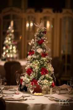 a christmas tree decorated with red and white flowers on a table in a fancy restaurant