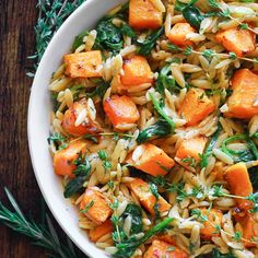 a white bowl filled with pasta and carrots on top of a green table cloth